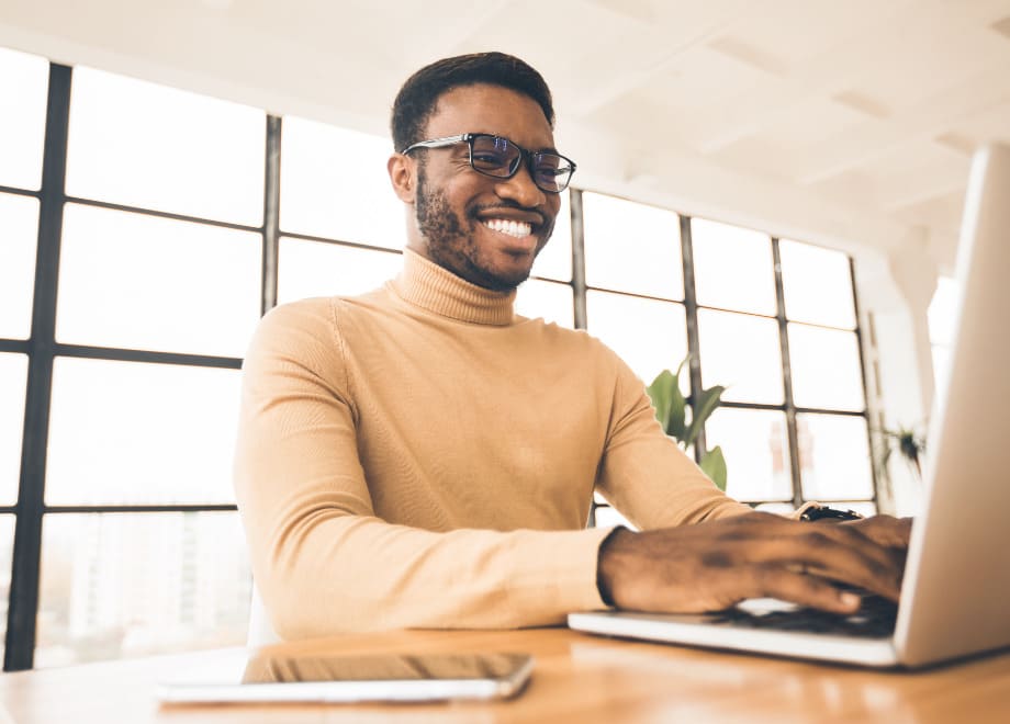 Imagem de um homem sorridente utilizando um notebook