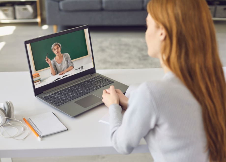 Imagem de uma mulher assistindo uma vídeo aula em modo tela cheia em um notebook